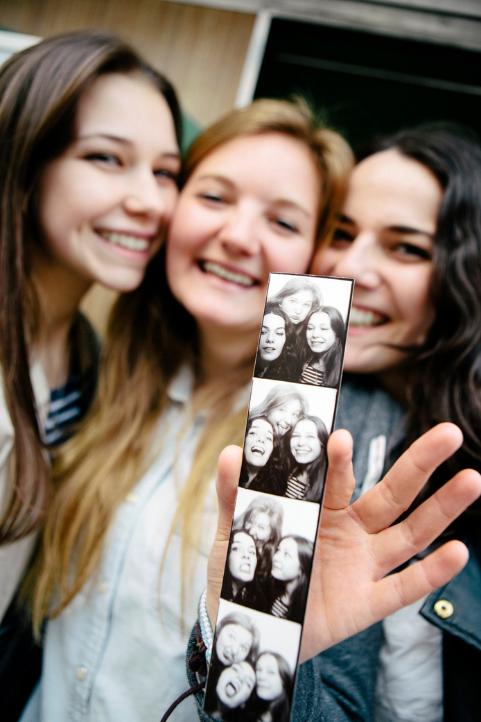 three teenager girls presenting their photo booth picture